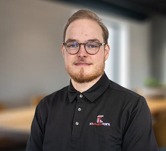 Mand med briller og kort skæg i sort poloshirt med logo fra KT Erhvervsbyg A/S