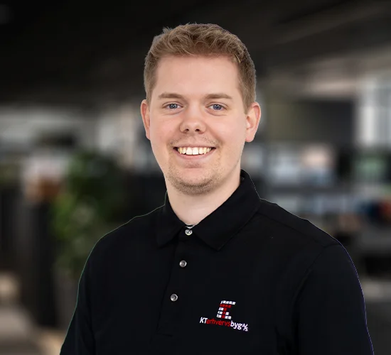 Smilende medarbejder i sort poloshirt med KT Erhvervsbyg A/S-logo