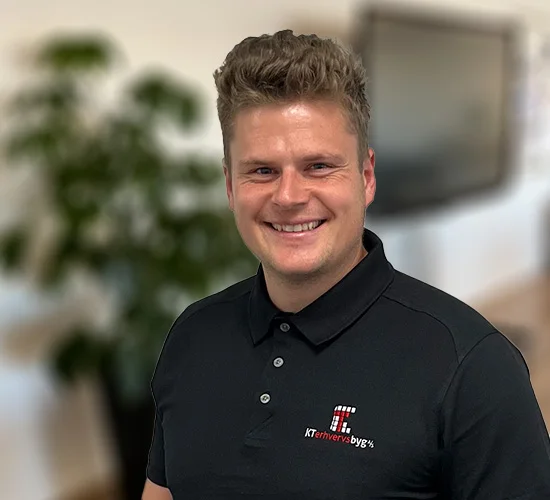 Smilende mand i sort poloshirt med logo fra KT Erhvervsbyg A/S
