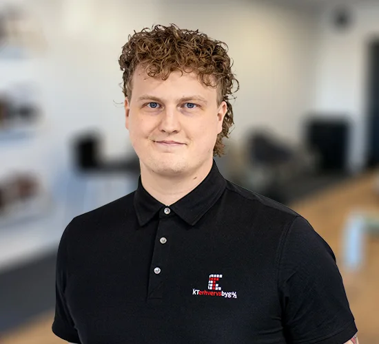 Portræt af en mand med krøllet hår i sort poloshirt med KT Erhvervsbyg A/S-logo