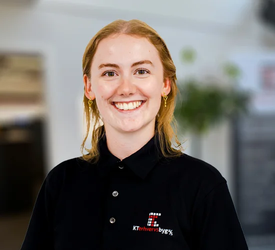 Smilende person i sort polo med logo for KT Erhvervsbyg A/S