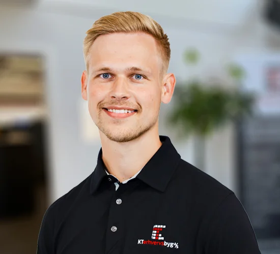 Smilende mand med kort, lyst hår og sort poloshirt med logo fra KT Erhvervsbyg A/S