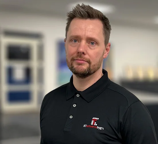 Mand med kort hår og skæg i sort poloshirt med logo fra KT Erhvervsbyg A/S