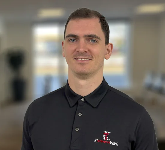 Smilende mand i sort poloshirt med logoet KT Erhvervsbyg A/S