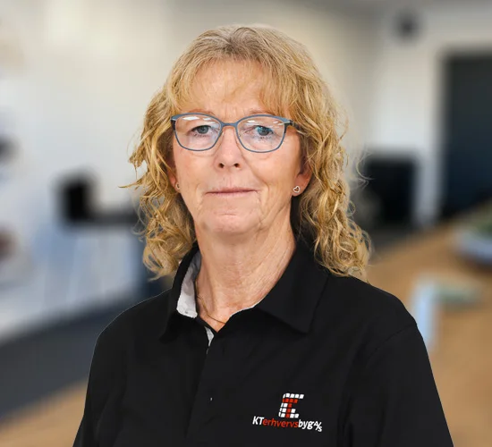 Medarbejder med lyst, krøllet hår og briller i sort poloshirt med logo fra KT Erhvervsbyg A/S