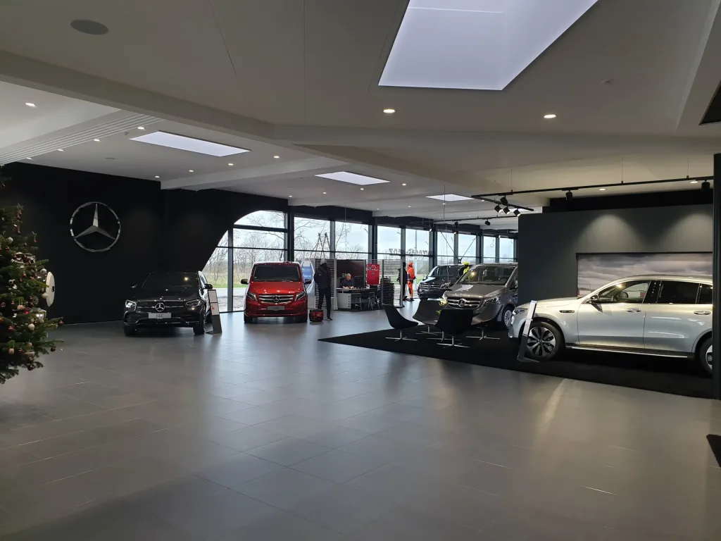 Biludstilling med flere Mercedes-biler, siddeområde og store vinduespartier
