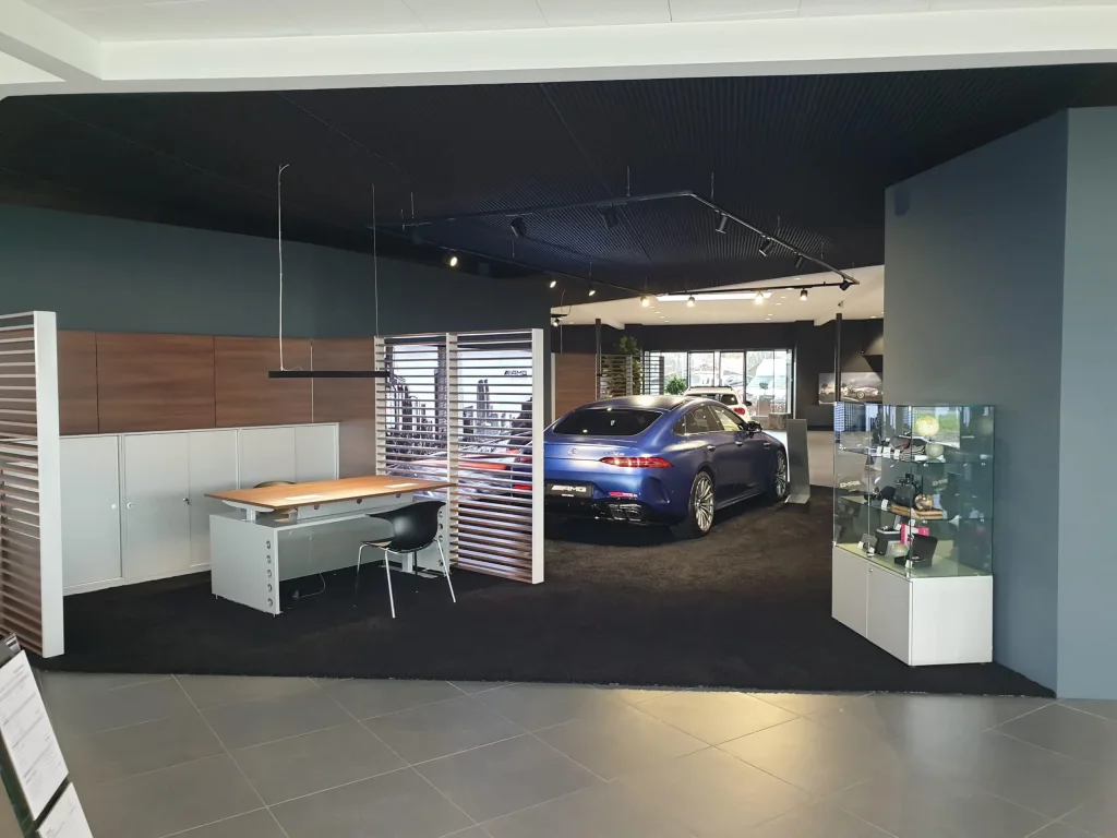 Blå bil i et showroom med skrivebord, lamelafskærmning og glasmontre