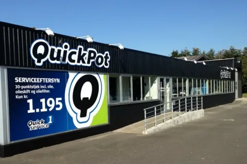 QuickPot-bygning med sort facade, store vinduer og adgangsrampe foran indgangen