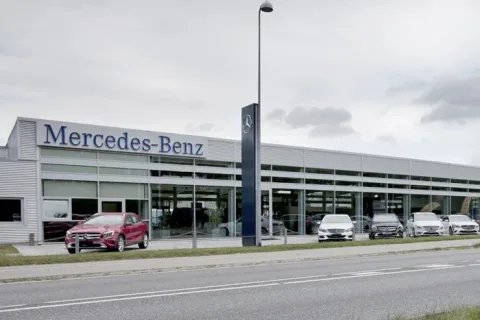 Mercedes-Benz-bilhus med stor glasfacade og biler parkeret foran