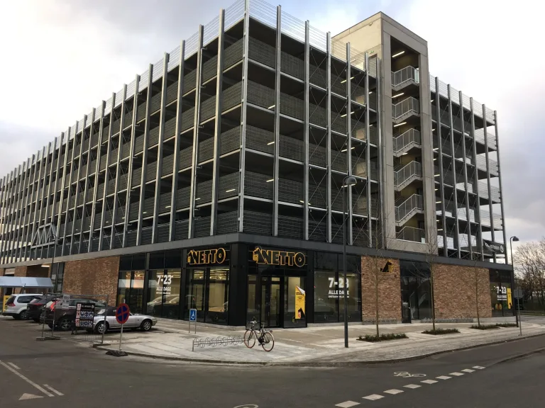 Netto-butik i stueetagen under et parkeringshus i flere etager med synlig udvendig trappe
