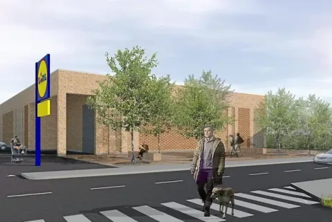 Visualisering af en Lidl-butik med murstensfacade, træer og en person med hund på fodgængerfeltet
