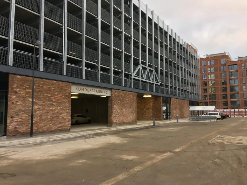 Parkeringshus i flere etager med indkørsel til kundeparkering i stueplan og murstensfacade