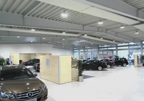 Lyst bilshowroom med flere udstillede biler, skillevægge og synlige loftsbjælker